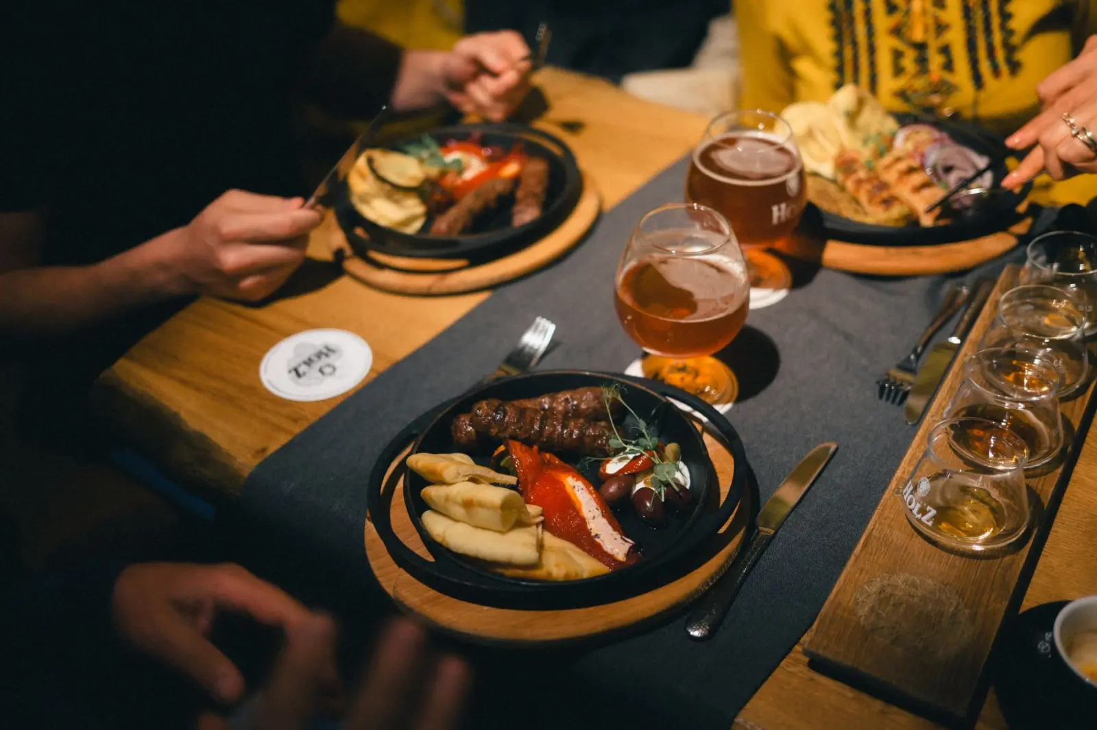 Beers and shared plates on a table at night