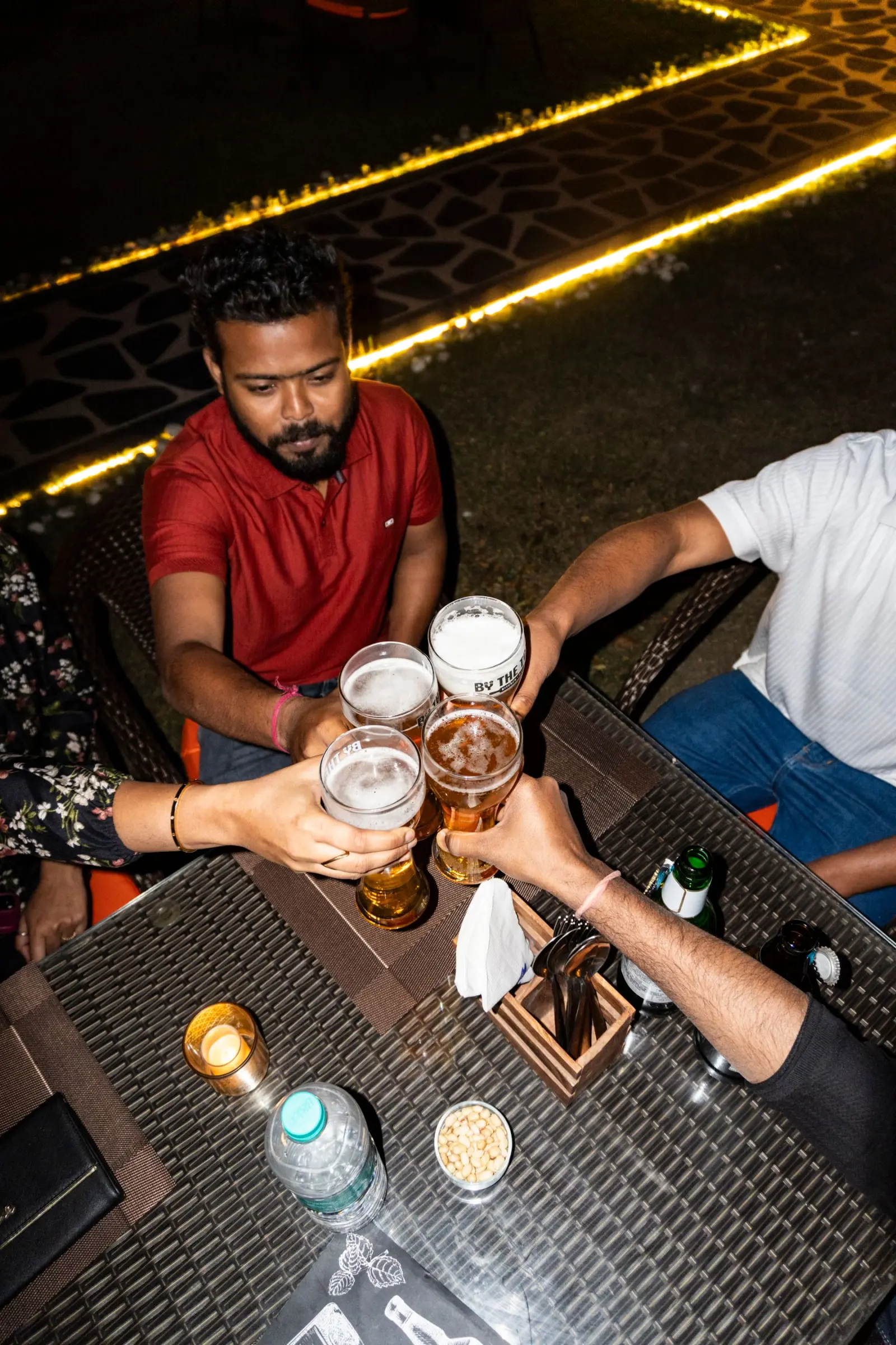 Friends raising their glasses at an outdoor table at night